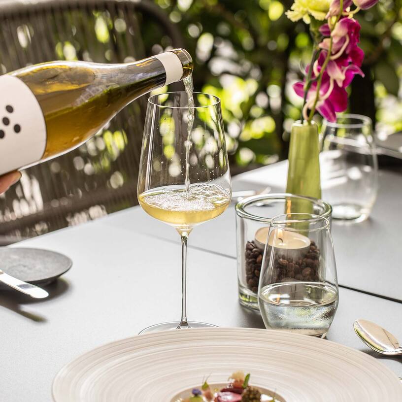 Wein einschenken an gedecktem Tisch im Aussenbereich Wein einschenken an gedecktem Tisch im Aussenbereich
