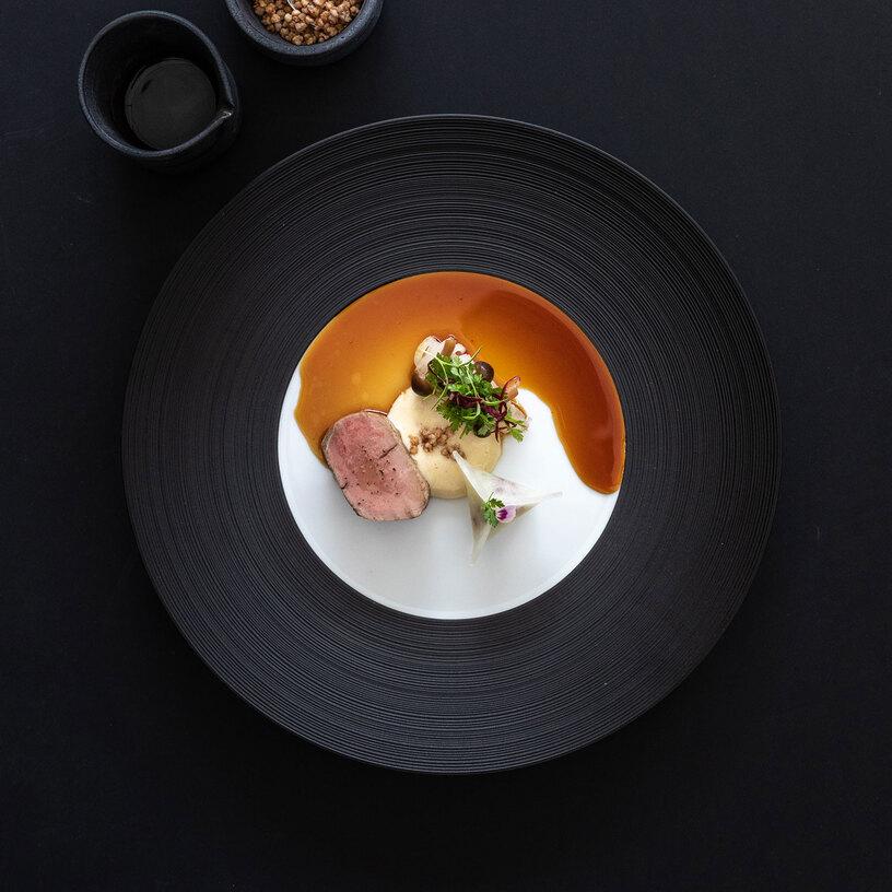 Gericht angerichtet auf schwarzem Teller Gericht angerichtet auf schwarzem Teller