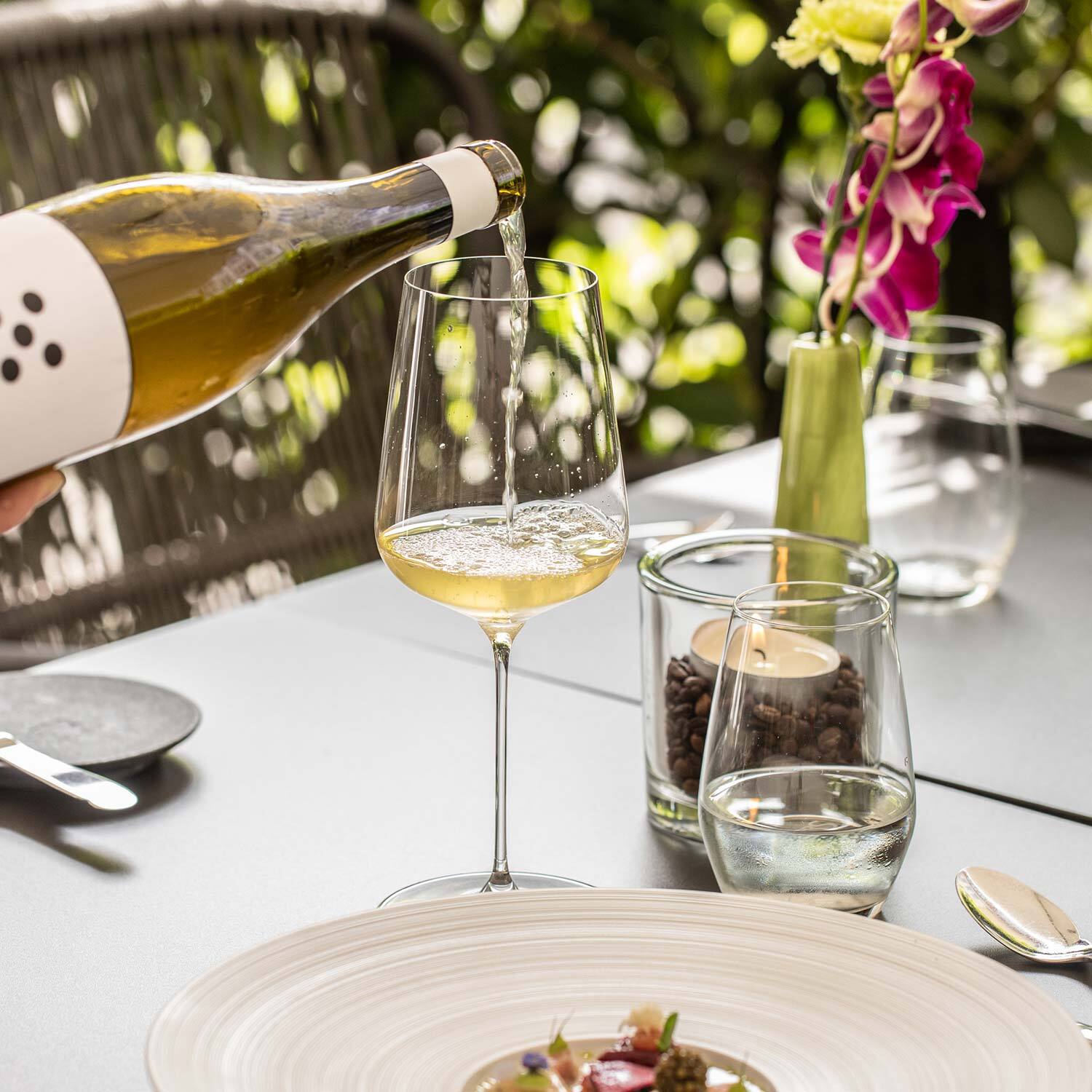 Wein einschenken an gedecktem Tisch aus der Aussenterasse Wein einschenken an gedecktem Tisch aus der Aussenterasse